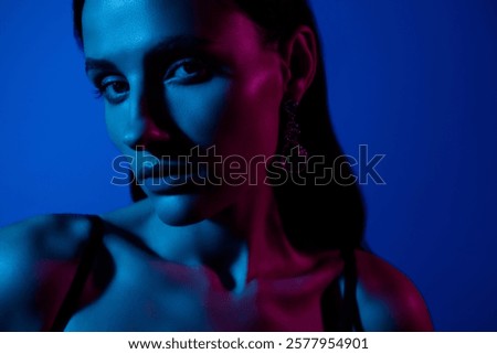 Creative portrait with dramatic lighting showcasing a woman's thoughtful expression in blue and pink tones