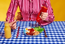 Creative Portrait Of Young Woman Wearing Vintage Style Clothes Ready To Eat Sandwich With Salad And Orange Juice. Vintage, Retro Style Interior. Blue, Red And Yellow. Surrealism
