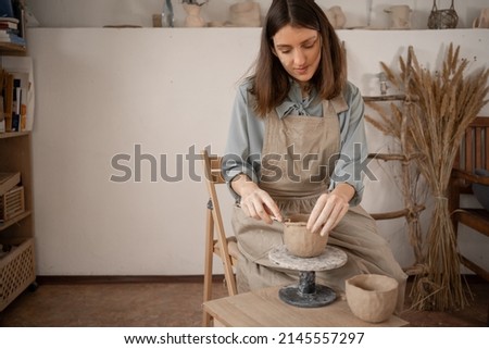 Similar – Young female sitting by table and making clay or ceramic mug