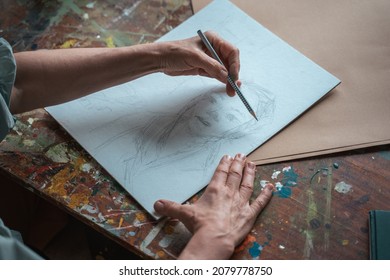 Creative professional female artist painting in her room, while sitting at the table - Shutterstock ID 2079778750
