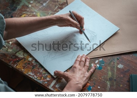 Creative professional female artist painting in her room, while sitting at the table