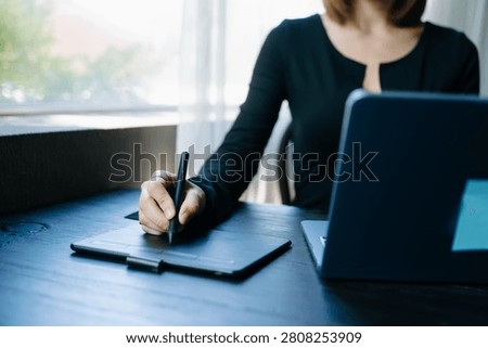 Creative professional using digital tablet and laptop for design, editing and business workflow in a modern workspace, showcasing technology, productivity