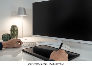 Creative professional's desk with a graphics tablet, keyboard, and blank monitor for mockup