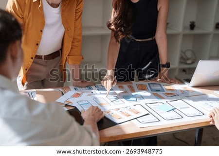 Creative professionals discussing wireframes and user experience designs for mobile application development. Modern office meeting