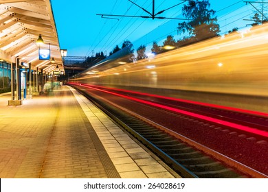 Creative railroad travel and transportation industry business concept: summer evening view of high speed commuter passenger train departing from railway station platform with motion blur effect