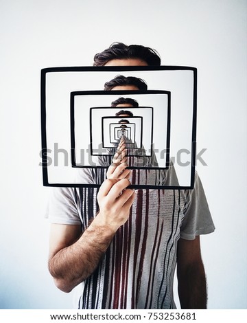 Creative recursion concept. Young man holding frame with recursion effect