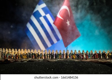 Creative Scale Decoration. Syrian Refugees (crowd) Looking On Greece And Turkey Flag Standing On Border. Concept Of Crisis Of War. Selective Focus