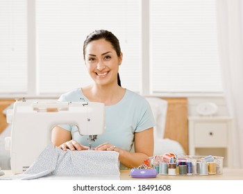 Creative, self-sufficient woman using sewing machine to make clothing