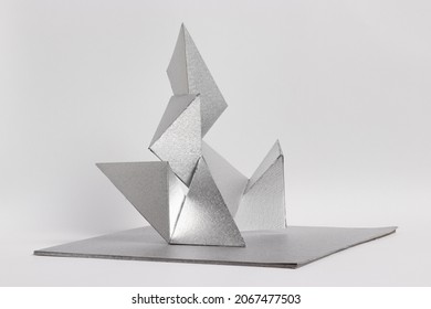 Creative Silver Designed Paper Sculpture Against Pastel White Background.