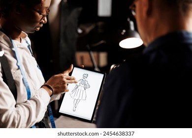 Creative skilled fashion designer showing atelier shop manager graphic design sketch drawing of wedding dress she is working on. Apprentice and master manufacturing bespoke sartorial outfit - Powered by Shutterstock