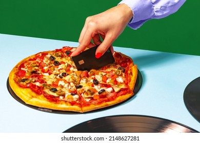 Creative slicing pizza. Food pop art photography. Female hands with italian pizza lying on vinyl discs on light tablecloth isolated on green background. Vintage, retro style interior.