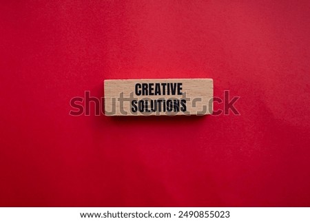 Creative solutions message written on wooden block with redbackground. Conceptual creative solutions symbol. Copy space.