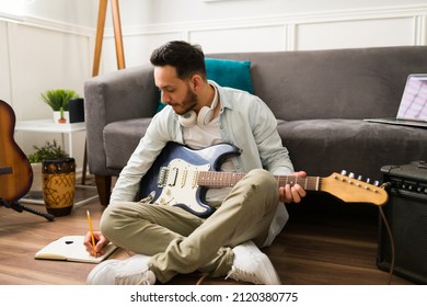 Creative songwriter writing the lyrics of a new song while playing the electric guitar at home