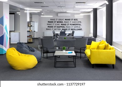 Creative Space.With Yellow Sofa And Yellow Bean Bag And Coffe Table In The First Plan And Conference , Meeting Table And Office Armchair On The Second Plan. With Motivation Words On The Wall