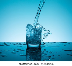 Creative splashing water in the glass on blue background.   - Shutterstock ID 614536286