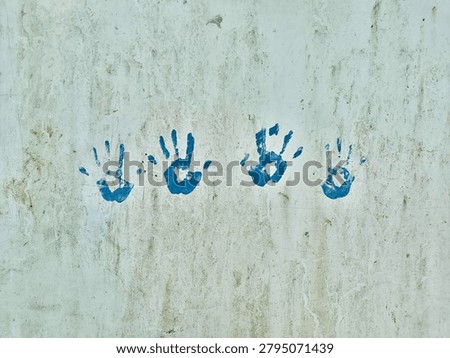 Creative student expression featuring blue handprints on an outdoor school wall.