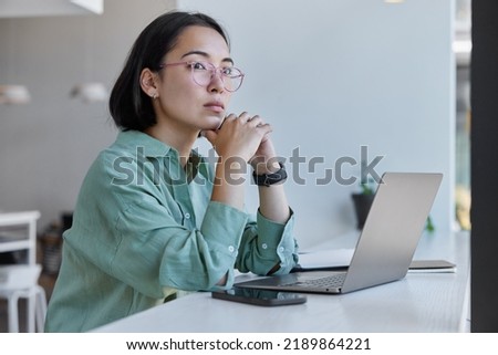 Creative student of journalism creates article for homework poses in coworkig space in front of laptop computer uses free internet connection searches information for project spends time on