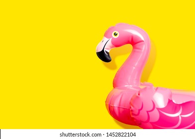 Creative summer beach concept. Inflatable pink mini flamingo on yellow background, pool float party. Flat lay, copy space. Flamingo Trend Inflatable Toy. Summer background
