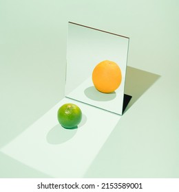 Creative summer fruit arrangement made of lime and orange in the mirror. Minimal still life concept. Not everything is as it seems inspiration. - Shutterstock ID 2153589001