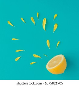 Creative summer layout made of lemon and yellow flower petals on bright blue background. Fruit minimal concept.