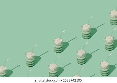Creative summer pattern made of iced matcha latte on pastel green background. Minimal healthy matcha latte concept. Trendy drink idea. Copy space.