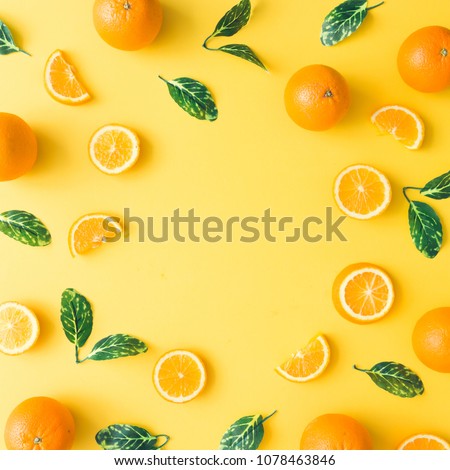 Creative summer pattern made of oranges and green leaves on pastel yellow background. Fruit minimal concept. Flat lay.