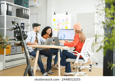 Creative team collaborates on a project with a laptop and digital screen in a modern office, recorded by a camera. Young business analyst evaluates environmental performance on screen in eco-strategy. - Powered by Shutterstock