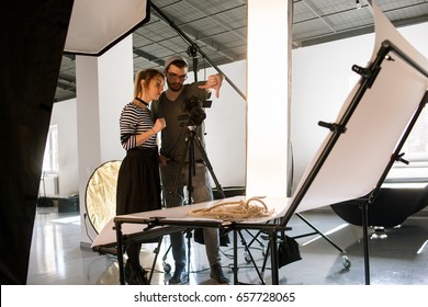 Creative team discussing shoot composition. Photographer taking work with assistant in studio interior. Photoshoot backstage, teamwork, brainstorming concept - Powered by Shutterstock