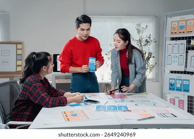 Creative team engaged in developing a mobile app interface, discussing design elements and user experience. Diverse group collaborating in a modern office setting with digital tools