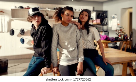 Creative Team Looking At Camera While Posing In Custom Apparel. Young Man And Women Working At Custom T-shirt, Clothing Printing Company. Startup Concept. Horizontal Shot