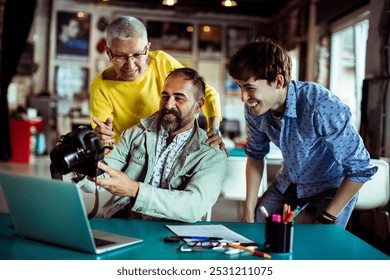 Creative team reviewing photos on camera in office setting - Powered by Shutterstock