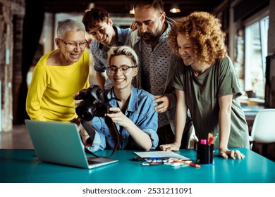 Creative team reviewing photos on camera in office setting - Powered by Shutterstock