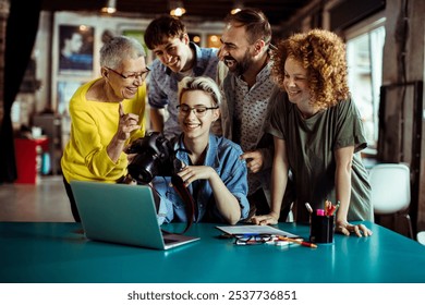 Creative team reviewing photos on camera in office setting - Powered by Shutterstock