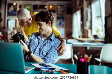 Creative team reviewing photos on camera in office setting - Powered by Shutterstock