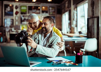 Creative team reviewing photos on camera in office setting - Powered by Shutterstock