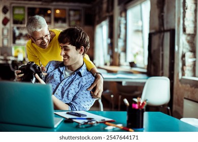 Creative team reviewing photos on camera in office setting - Powered by Shutterstock