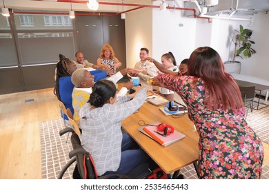 Creative team stacking hands during meeting at table in office