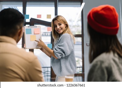 Creative team working together for startup project. Team building. Strategy planning. Brainstorming. Collaborate. Successful scrum master showing finger on sticky note, helping team reach consensus. - Shutterstock ID 1226367661
