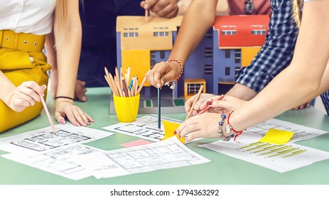 Creative team of young modern architects working on blueprint during brainstorm meeting – Engineers discussing construction plans and project in office – House designers at work - Shutterstock ID 1794363292