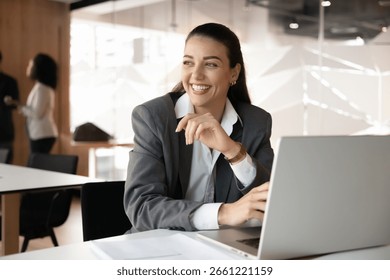 Creative thinking and visualization. Cheerful young businesswoman sit by laptop at workplace desk look away with dreamy smile create new solution reflect on future goals take mindful break. Copy space