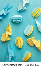 Creative Top view flat lay holiday composition Easter eggs funny bunny on blue paper background, copy space. Origami papercraft Easter day seasonal pattern 