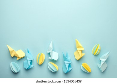 Creative Top view flat lay holiday composition Easter eggs funny bunny on blue paper background, copy space. Origami papercraft Easter day seasonal pattern 