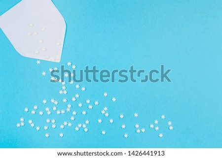 Creative Top view flat lay winter frame. Concept Mockup pattern made of small white snowflakes letter envelope pastel blue background copy space minimalism Template anniversary design invitation cards