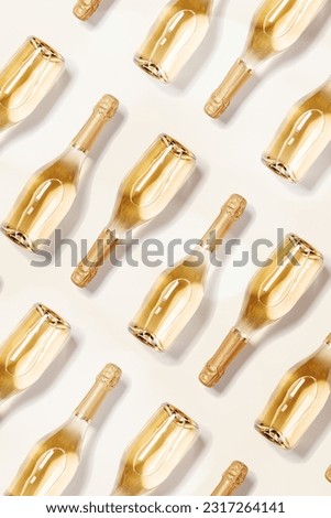 Creative top view minimal pattern of bottles of white sparkling wine, glass champagne bottle on beige background, sunlight, shadow. Festive drink concept. Summer alcohol drinks wine list, flat lay