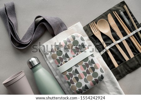 Creative top view, zero waste packed lunch kit, takeaway lunch box set on cotton bag, organizer of bamboo cutlery, reusable box and coffee-to-go cup. Sustainable lifestyle, flat lay on craft paper.