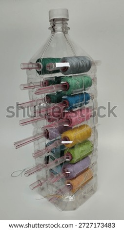 Creative upcycling idea using a used plastic bottle to store colorful sewing threads. Isolated on white background, perfect for sustainability, craft hobbies, and zero waste lifestyle concepts.