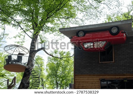 Creative Upside Down Car Installation on Woodland Building With Spiral Treehouse Staircase.