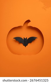 Creative vertical Halloween composition showing a pumpkin cutout with a bat silhouette on orange