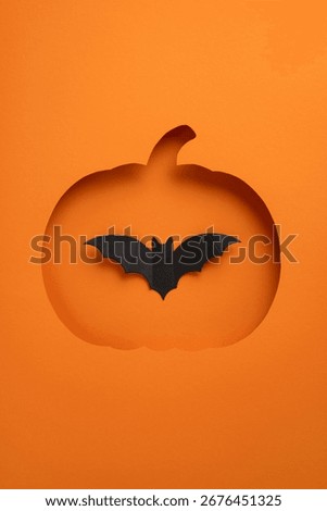 Creative vertical Halloween composition showing a pumpkin cutout with a bat silhouette on orange