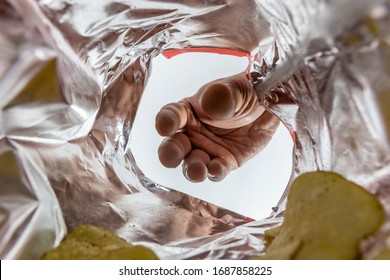 Creative View From Inside A Bag Of Potato Chips With A Hand Reaching For A Chip